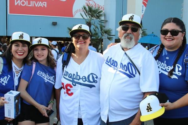 Five people posing with Cal State LA baseball caps at Dodger Stadium